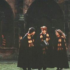 three young people dressed in harry potter robes talking to each other outside an old building