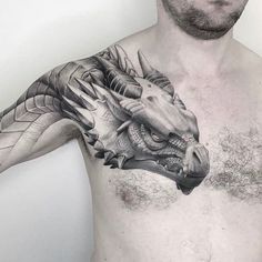 a man's chest with a dragon tattoo on his left arm and the head of a snake