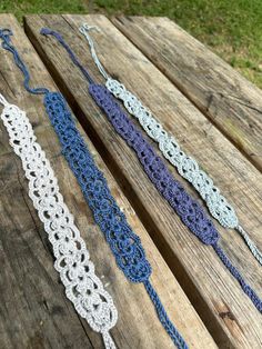 three crocheted lace garters sitting on top of a wooden picnic table