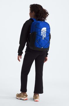 the north face backpack in blue and black is shown from back, with an open zippered pocket