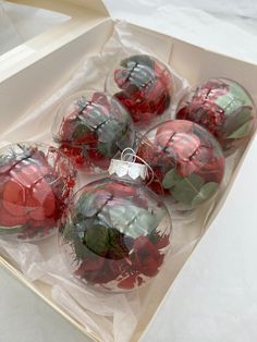 six red and green christmas ornaments in a box