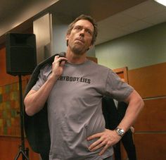 a man standing in front of a speaker with his hands on his hips while wearing a gray shirt