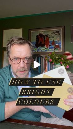 a man sitting at a table with a book in front of him that says how to use bright colours