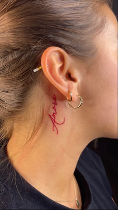 a woman with a small tattoo on her neck and behind the ear that reads, i love you