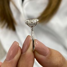 a close up of a person holding a ring with a diamond on the middle of it