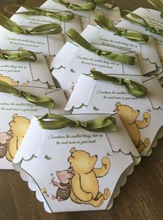 winnie the pooh baby shower gift tags with green satin ribbon and matching bow on wooden table