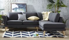 a living room with a gray couch and pillows on the floor next to a potted plant