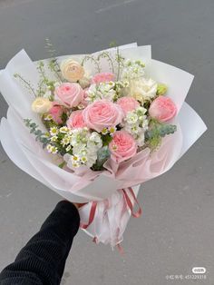 a person holding a bouquet of pink and white flowers