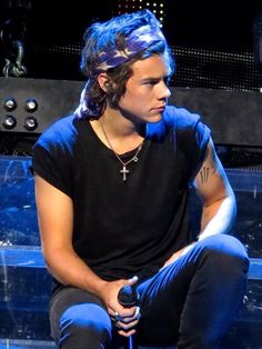 a young man with blue hair sitting on the ground holding a microphone in his hand