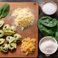 pasta shells, spinach and cheese are on a cutting board next to other ingredients