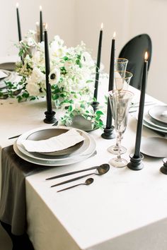 the table is set with white flowers and black candles