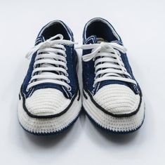 a pair of blue and white tennis shoes with laces on the bottom, sitting on a white surface