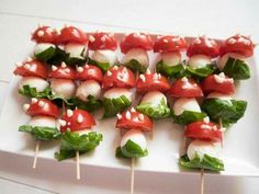 several skewers with vegetables and sauce on them sitting on a white platter