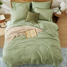 a bed with green sheets and pillows on it