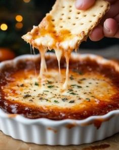 someone dipping cheese into a dish with crackers