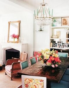 a dining room table with chairs and a chandelier hanging from the ceiling above it