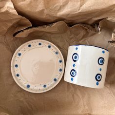 a white and blue plate sitting next to a cup on top of a brown paper bag