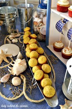 a table topped with cupcakes and muffins on top of a blue cloth