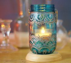 a lit candle in a glass jar on a table