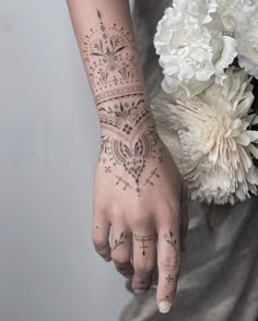 a woman's hand with a tattoo on it holding a bouquet of white flowers