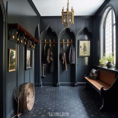 an elegant entryway with dark blue walls and wood bench, coat rack, and mirror