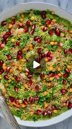 a white bowl filled with lots of food on top of a marble counter next to silverware