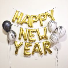 balloons and streamers with the words happy new year written in gold, silver and black