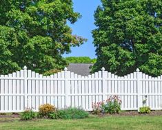 a white picket fence with trees in the background