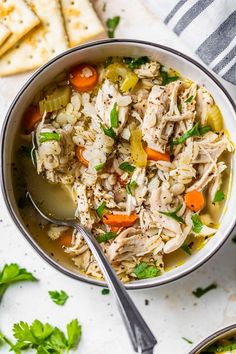 a bowl filled with chicken and rice soup next to crackers