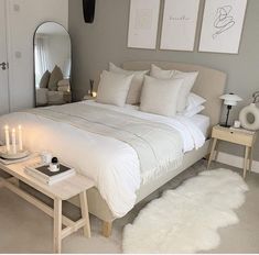 a white bed sitting in a bedroom next to two tables with candles on top of it