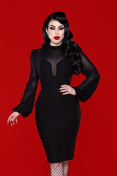 a woman wearing a black dress with sheer sleeves and fishnet stockings, standing in front of a red background