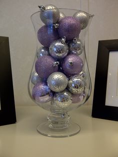 a glass vase filled with purple and silver ornaments