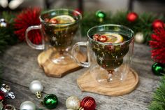 two mugs filled with hot drink surrounded by christmas decorations