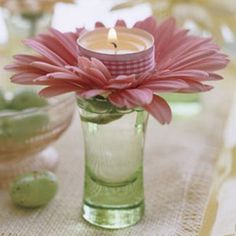 a flower in a glass vase with a candle on the table next to other dishes