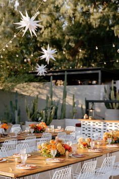 an outdoor dining area with white chairs and wooden tables set up for a dinner party