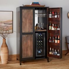 a cabinet with wine glasses and bottles in it next to a vase on the floor