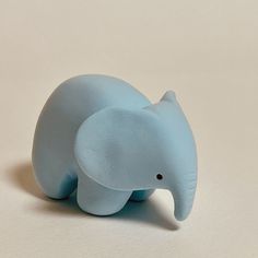 a small blue elephant figurine sitting on top of a table next to a white wall