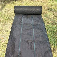 a roll of black tarp laying on top of the grass next to a field