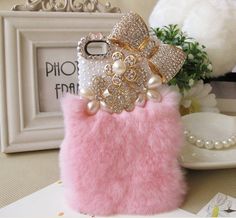 a pink cell phone case with pearls and bows on the front, sitting on a table