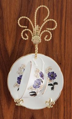 a white plate with purple flowers hanging from it's side on a wooden surface