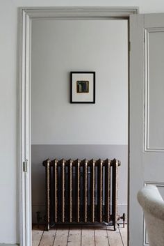 an old radiator in the corner of a room with white walls and wood floors