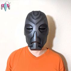 a man in an orange shirt is wearing a batman mask