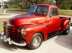 an old red pick up truck parked in a driveway