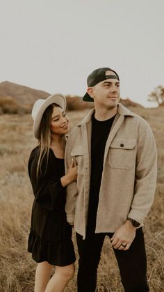 a man and woman are standing together in the grass