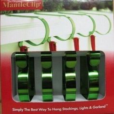 three green tape holders are on display in a box with red ribbons hanging from it's sides