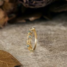 a gold ring with blue stones on it sitting on the ground next to some leaves