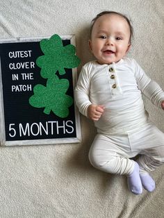 a baby laying on the floor next to a sign that says quiet clover in the patch