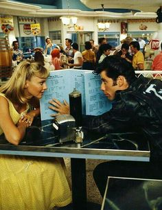 a man sitting at a table next to a woman reading a menu in a restaurant