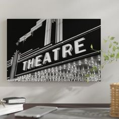 a black and white photograph of the theatre sign in front of a laptop on a desk