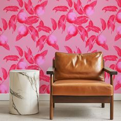 a leather chair sitting in front of a pink wall